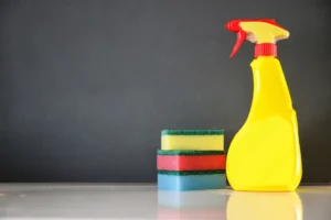 Frasco borrifador de produto de limpeza ao lado de esponjas