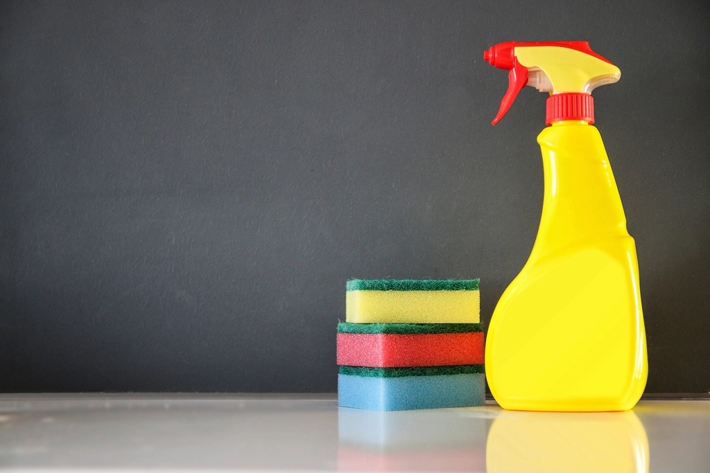 Frasco borrifador de produto de limpeza ao lado de esponjas